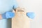 Male hand in blue medical gloves holds craft paper bag on white background. Delivery against Coronavirus 2019-nCov in pandemic
