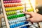 Male hand calculating beads on rainbow abacus