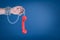 Male hand chained to red retro telephone receiver on blue background