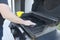 The male hand cleans the black grill with a soft brush. Grill for frying meat. Cleaning the outdoor gas grill