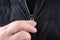 Male hand closing zipper on black jacket closeup