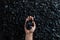 Male hand with coal on the background of a heap of coal, coal mining in an open pit quarry, copy space. Fossil fuels,