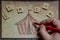 A male hand is coloring a drawing representing a circus tent with a red pencil