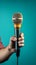 A male hand confidently holds a microphone against a vibrant blue background.