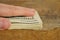 Male hand covering a heap of American money US currency, USD on the wooden background as a symbol of wealth