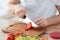 Male hand cutting tomato on board with knife