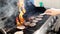 Male hand flipping hamburger meat above the fire of iron barbecue grill