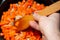 Male hand frying onions with carrots, wooden spatula