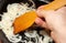 Male hand frying onions, wooden spatula