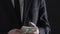 Male hand giving bribe money to businessman, corruption and venality, crime