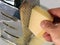 male hand grating Parmesan cheese on a metall kitchen grater, closeup of using a grater