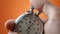 Male hand holding analogue stopwatch on orange color background. Time start with old chronometer man presses start