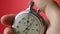 Male hand holding analogue stopwatch on red background. Time start with old chronometer man presses start button in the