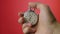 Male hand holding analogue stopwatch on red background. Time start with old chronometer man presses start button in the