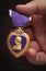 Male Hand Holding the Armed Forces Purple Heart Medal