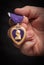 Male Hand Holding the Armed Forces Purple Heart Medal