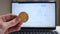 Male hand holding cryptocurrency coin over laptop background showing graph