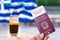 Male hand holding an european passport with a covid-19 immunity certificate over the Greek flag and a frape coffee.