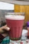 A male hand holding a glass cup with strawberry juice bought at the Pisac market