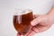 Male hand holding a glass of homemade craft beer on white background. Craft beer brewing from grain barley pale malt