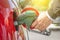 Male hand holding green pump filling gasoline