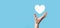 Male hand holding heart , like icon on blue background. Kindness, charity, pure love and compassion concept.Banner with copy space