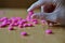 Male hand holding a pink pill as a symbol of pharmacy