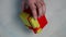 Male hand holding a red and yellow gift box.