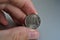 Male hand holding a shiny silver coin of one Ruble (Rouble) as symbol of Russian currency