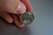 Male hand holding a shiny silver coin of one Ruble (Rouble) as symbol of Russian currency