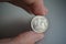 Male hand holding a shiny silver coin of one Ruble (Rouble) as symbol of Russian currency