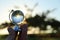 male hand holding small crystal globe in front of sunset