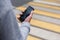 Male hand holding smartphone with blank screen on pedestrian crossing