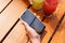 Male hand holding smartphone and two lemonades on brown red glossy boards wooden table. Top view, mockup, close-up