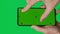 Male hand holding a smartphone with vertical green chroma key screen isolated on green background. Different signs and