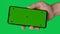 Male hand holding a smartphone with vertical green chroma key screen isolated on green background. Different signs and