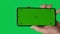 Male hand holding a smartphone with vertical green chroma key screen isolated on green background. Different signs and