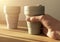 Male hand holding or taking eco coffe cup from wooden table with beautiful daylight from window