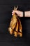 Male hand holding three smoked breams on black wooden background