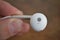 Male hand holding white modern earphone in futuristic design