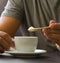 Male hand holding wooden spoon with sugar over cup of coffee or tea. Stop sugar. Campaign against diabetes, obesity, dental caries