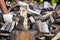 Male hand holds an axe stuck in a stump with a pile of chopped firewood on the background outdoors in summer