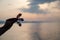 A male hand holds a fish chopsticks helper on the sea background. Sunset, silhouette. Copy space