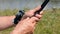 Male hand holds fishing rod on the background of the river close-up. Fisherman holds a fishing rod. River fishing.