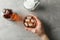 Male hand holds glass of whiskey on grey background with bottle and ice cubes