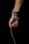 Male hand holds a rope on a black background.