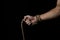 Male hand holds a rope on a black background.