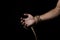 Male hand holds a rope on a black background.