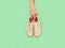 Male hand holds unbranded beige sneakers isolated on green background with copy space. Top view