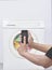 Male hand operate washing machine with his mobile phone